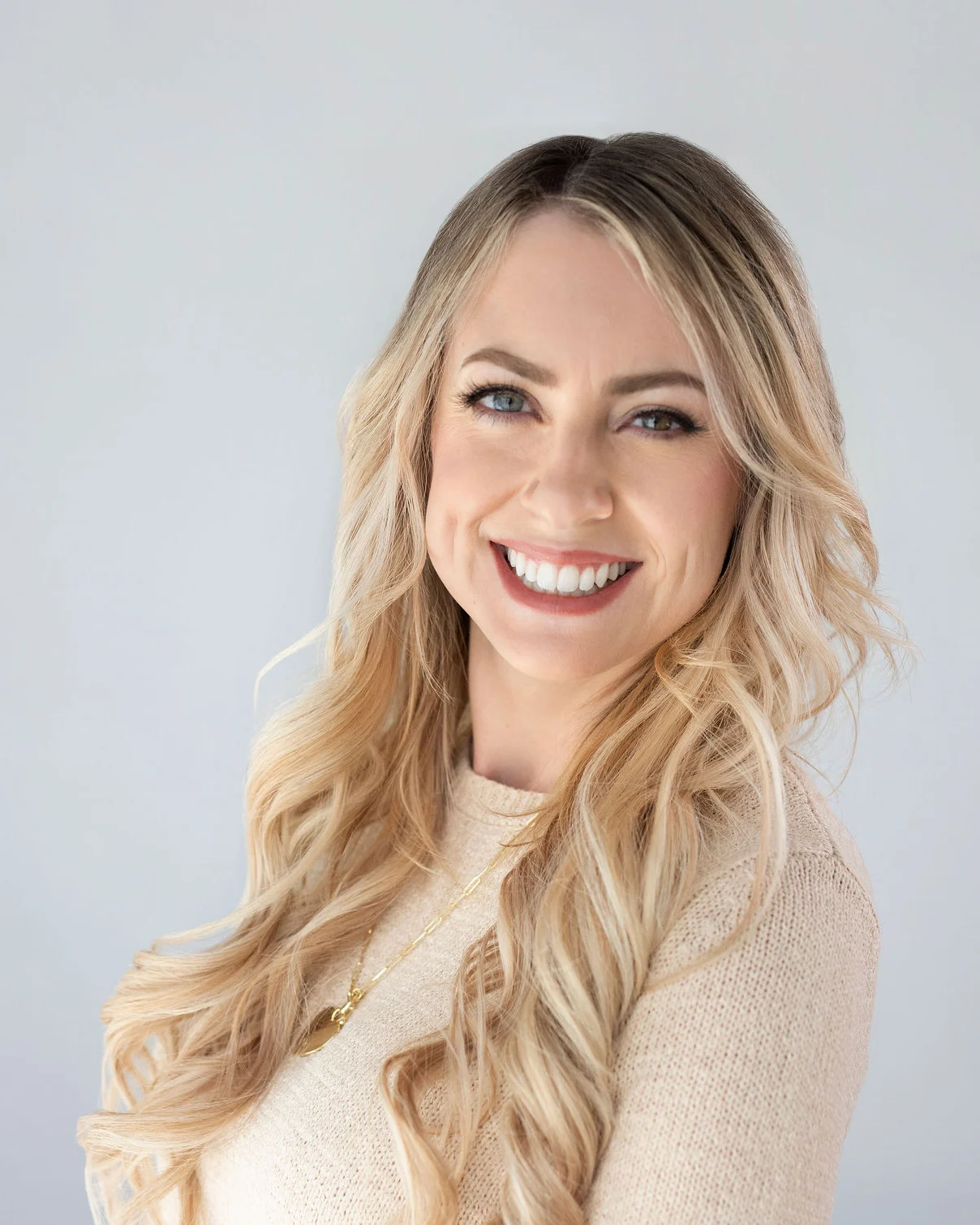 Megan Mickelson, smiling, in a cream sweater against a soft grey backdrop